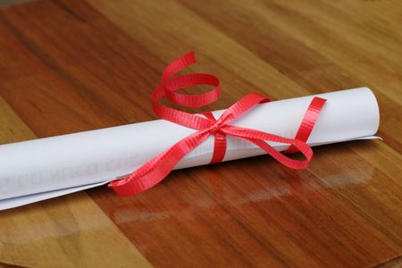 scroll with red ribbon on wood backgroundの写真素材