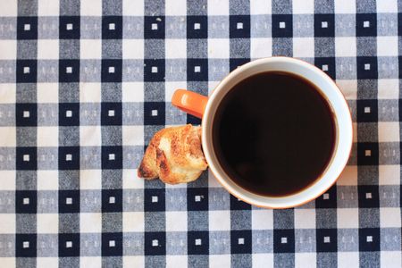 cup of coffee on blue and white gingham tableclothの写真素材