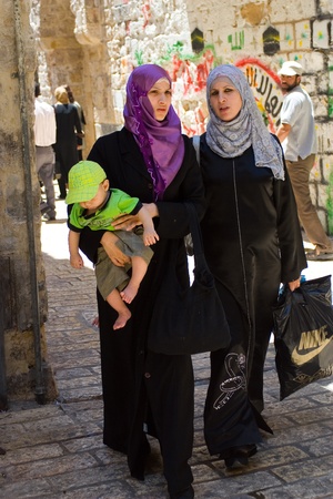 Old City, Jerusalem, Israel - July 17, 2009: Two Arab Women walking on traditional costume, one holding baby. Old City, Jerusalem, Israel - July 17, 2009: Two Arab Women walking on traditional costume, one holding baby.