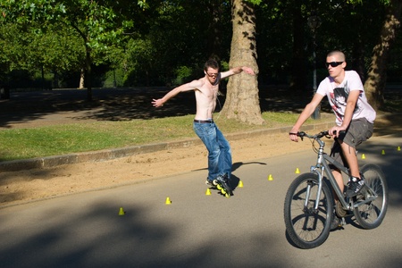 Hyde Park, London, United Kingdom - August 31, 2009. Roller (caucasian man) skating slalom and bicyclist.のeditorial素材