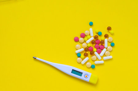 thermometer and pills on yellow backgroundの写真素材