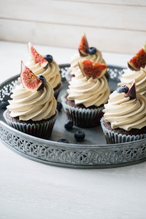 Chocolate cupcake with caramel frosting on white wooden background close up selective focusの写真素材