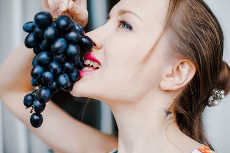 A girl holds a black grape. Sweet foodの写真素材