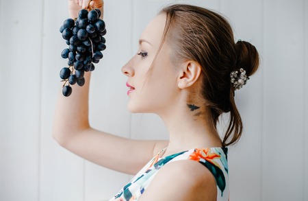 A girl holds a black grape. Sweet foodの写真素材