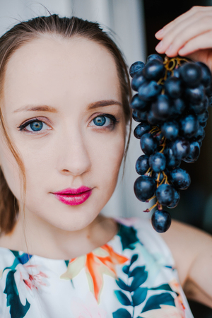A girl holds a black grape. Sweet foodの写真素材
