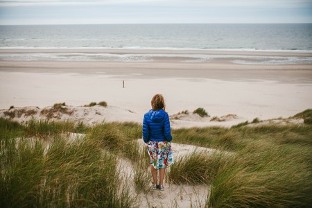 The girl looks at the sea from the back.の写真素材