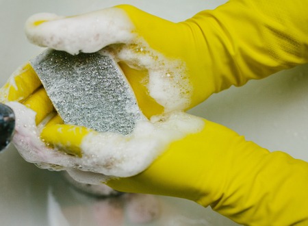hands in yellow gloves keep the sponge in the foamの写真素材