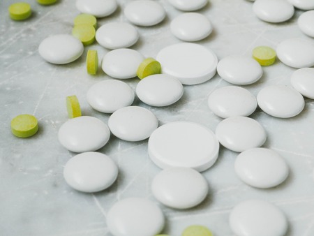 White and yellow pills on white background. Heap of capsules, drug. Healthcare.の写真素材