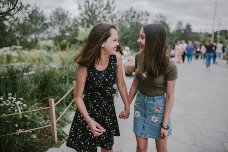 Two girlfriends hold hands and laughの写真素材