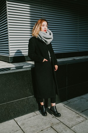 Asian girl looks in black coats on the streetの写真素材