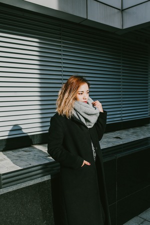 Asian girl looks in black coats on the streetの写真素材
