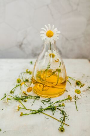 natural oil with chamomile in a glass flask on a light backgroundの写真素材
