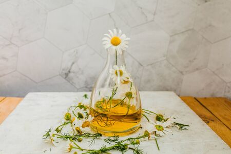 natural oil with chamomile in a glass flask on a light backgroundの写真素材