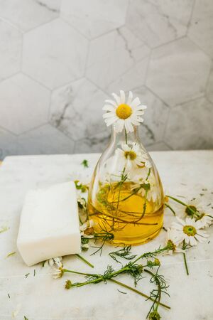natural oil with chamomile in a glass flask on a light backgroundの写真素材