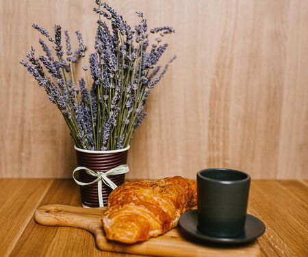 A croissant and a cup of coffee on a wooden board, foodの写真素材