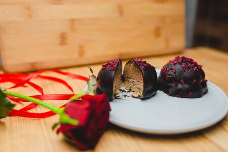 Two chocolate cakes on a plate with a red rose. Dessert on February 14の写真素材