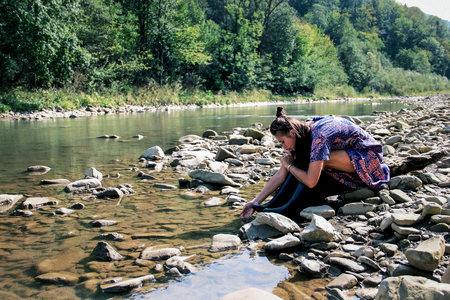 a lonely girl sits on the bank of a mountain riverの写真素材