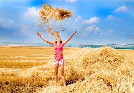Harvest, girl throwing grass on  background of the skyの写真素材