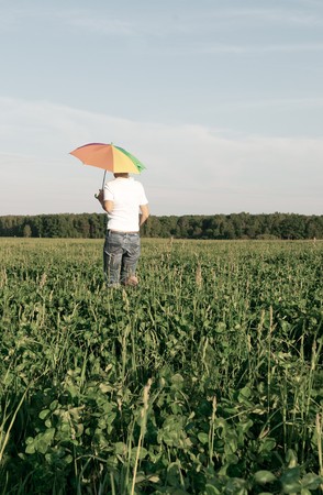 woman under blue sky with umbrella in fieldの写真素材
