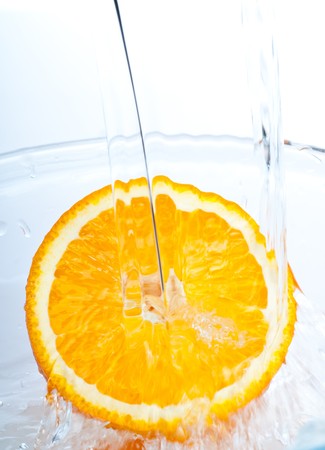 orange into water splash on whiteの写真素材