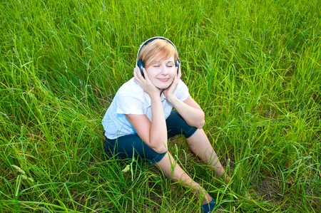 Beautiful woman  at grass with headphonesの写真素材