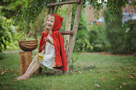 Cute little girl playing red riding hood in summer gardenの写真素材