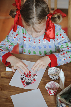 cute child girl making christmas tree handmade postcardsの写真素材