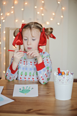 cute child girl making christmas kids handprints post cardsの写真素材
