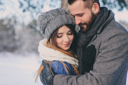 happy loving couple walking in snowy winter forest, spending christmas vacation together. Outdoor seasonal activities. Lifestyle capture.の写真素材