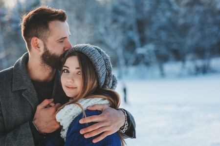 lifestyle shot of young happy couple walking in snowy forest, spending winter vacation outdoors