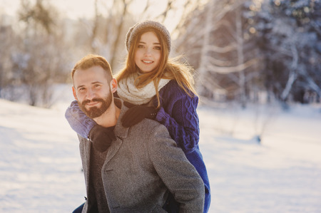 happy loving couple walking in snowy winter forest, spending christmas vacation together. Outdoor...