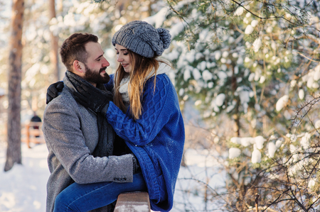 happy loving couple walking in snowy winter forest, spending christmas vacation together. Outdoor seasonal activities. Lifestyle capture.の写真素材