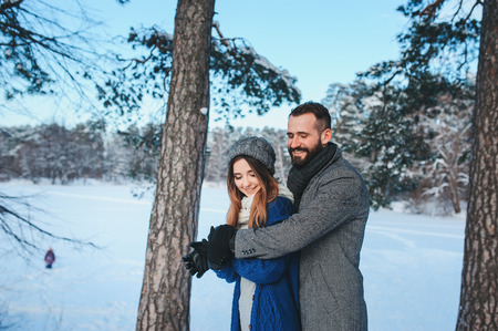 happy loving couple walking in snowy winter forest, spending christmas vacation together. Outdoor seasonal activities. Lifestyle capture.の写真素材