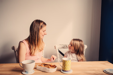 pregnant mother and toddler daughter having breakfast at home, cozy lifestyleの写真素材