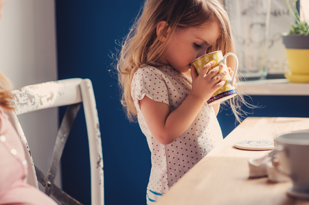 pregnant mother and toddler daughter having breakfast at home, cozy lifestyleの写真素材