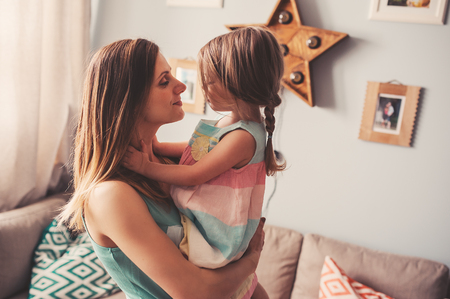 Happy pregnant mother and toddler daughter playing at homeの写真素材