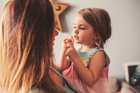 happy pregnant mother and toddler daughter playing at home in cozy interior, lifestyle candid captureの写真素材