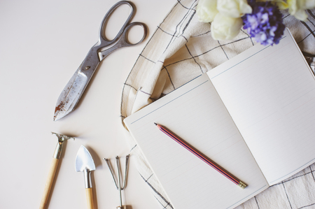 spring gardener plan or to do list on table with empty space on white background. Flat lay, top view seasonal composition with flowers, garden tools and weekly plannerの写真素材