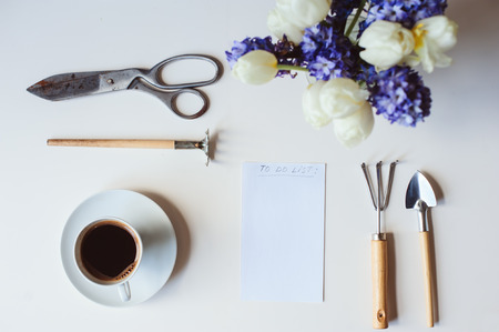 spring gardener plan or to do list on table with empty space on white background. Flat lay, top view seasonal composition with flowers, garden tools, coffee and weekly plannerの写真素材