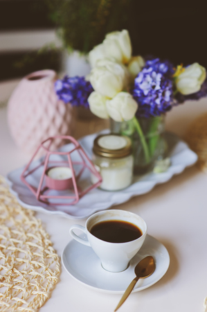 Morning coffee, spring decorations at home on the table in modern scandinavian style with flowers and aromatic candles. Slow living and hygge conceptの写真素材