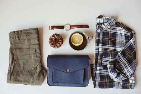 hipster or traveller woman casual fashion set flat lay. Plaid shirt, blue cross body bag  and khaki pants on white background with cup of tea. Stylish outfit top view.の写真素材