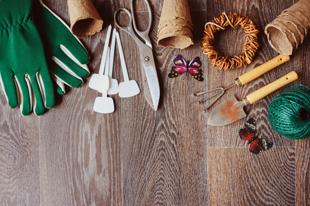Spring gardener table top view with tools, gloves, peat pots and garden labels on brown wooden background. Flat lay composition, seasonal preparations for sawing seedsの写真素材