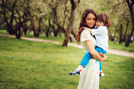 happy mom hugs and kiss toddler kid son outdoor in spring or summer. Loving family and mothers day concept.の写真素材