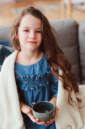 child girl drinking hot tea to recover from flu. Healing kids and protect immunity from seasonal virus, health conceptの写真素材