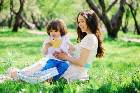 happy family on picnic for mothers day. Mom and toddler son eating sweets outdoor in spring or summer park. の写真素材