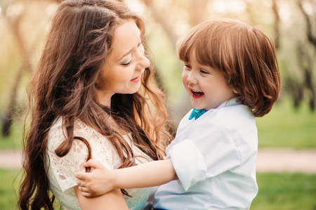 happy mom hugs and kiss toddler kid son outdoor in spring or summer. Loving family and mothers day concept.の写真素材
