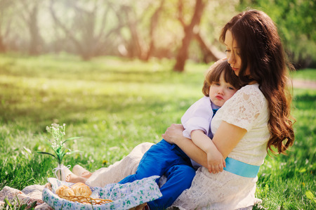 mom hugs sad toddler son outdoor on the walk. Happy loving family and mothers day concept. の写真素材