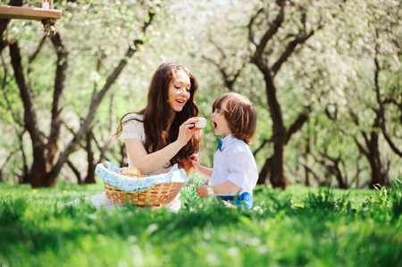 happy family on picnic for mothers day. Mom and toddler son eating sweets outdoor in spring or summer park. の写真素材