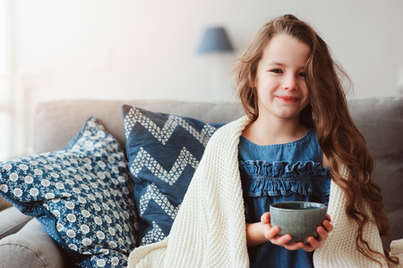 child girl drinking hot tea to recover from flu. Healing kids and protect immunity from seasonal virus, health conceptの写真素材