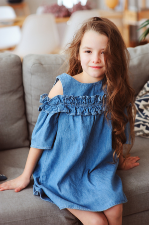 cute happy 5 years old child girl relaxing alone at home on cozy couchの写真素材